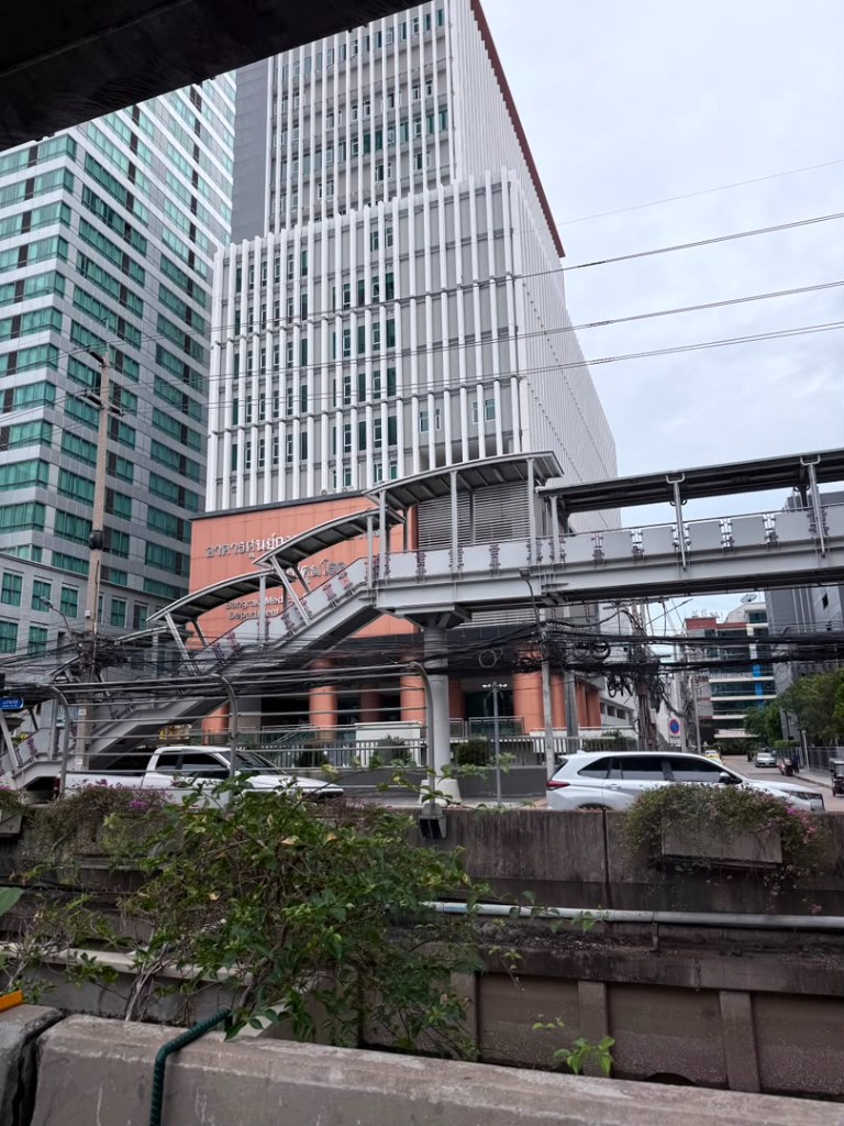 Sathorn street with a pedestrian overpass, overhead wires, and Bangrak Medical Center
